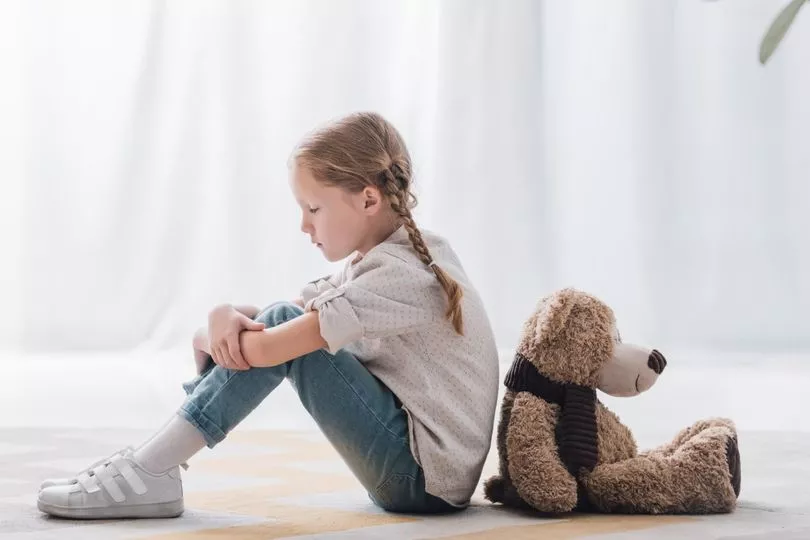 תמונה של ילדה יושבת גב אל גב עם דובי חום