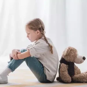 תמונה של ילדה יושבת גב אל גב עם דובי חום